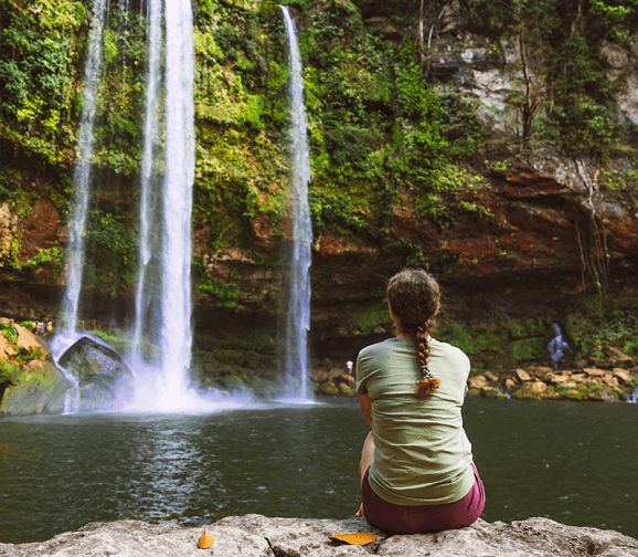 Una mujer mirando hacia una cascada
